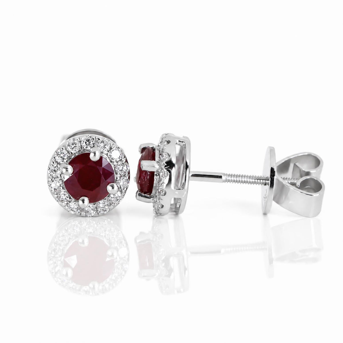 View of the front and side of a pair of ruby and diamond earrings with screw back closure on a white background with soft reflection