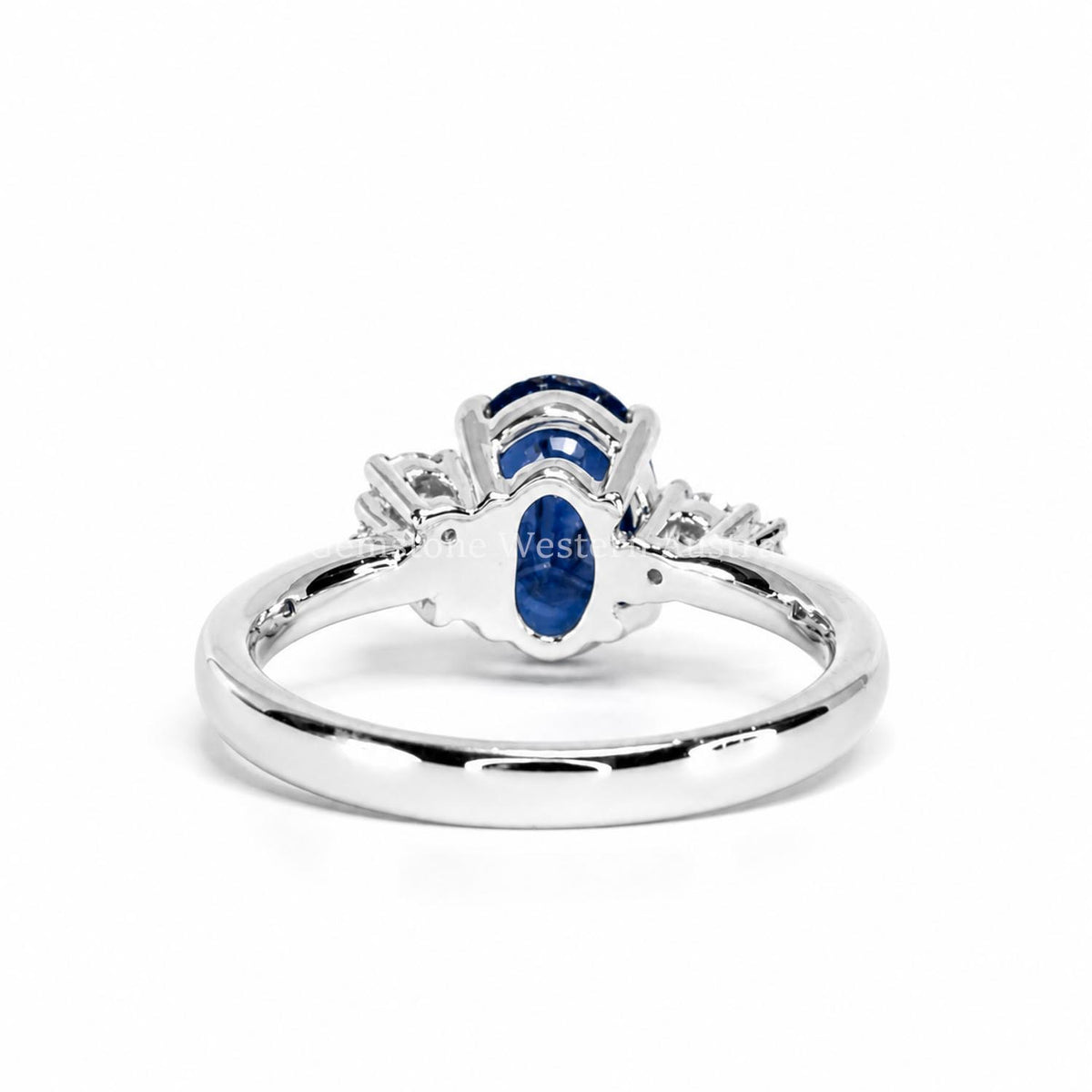 A platinum ring featuring a central royal blue sapphire and a cluster of diamonds, set on a polished platinum band. The ring is photographed on its back view on a clean white background with a faint watermark across the center.