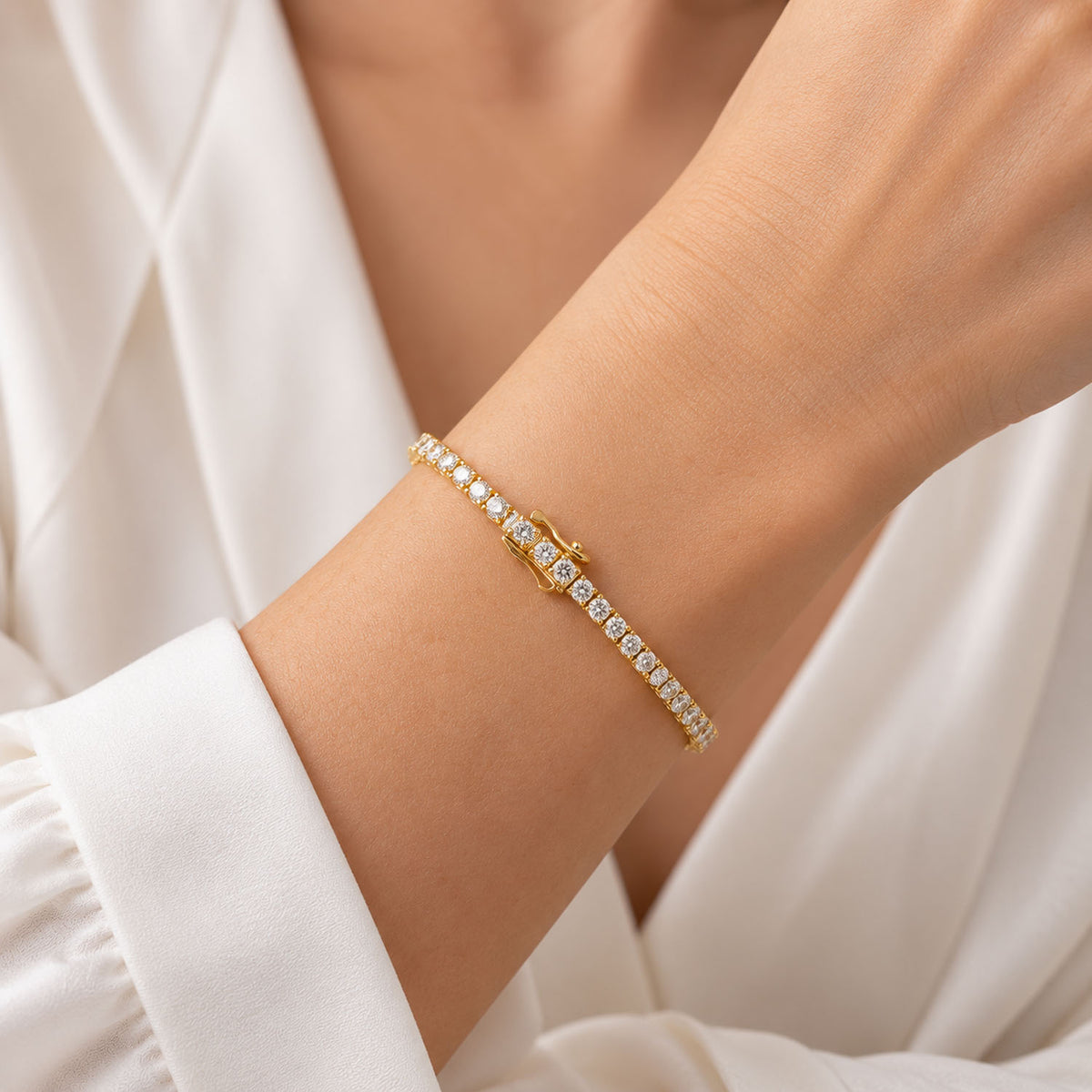 a yellow gold diamond tennis bracelet being worn shown on a wrist