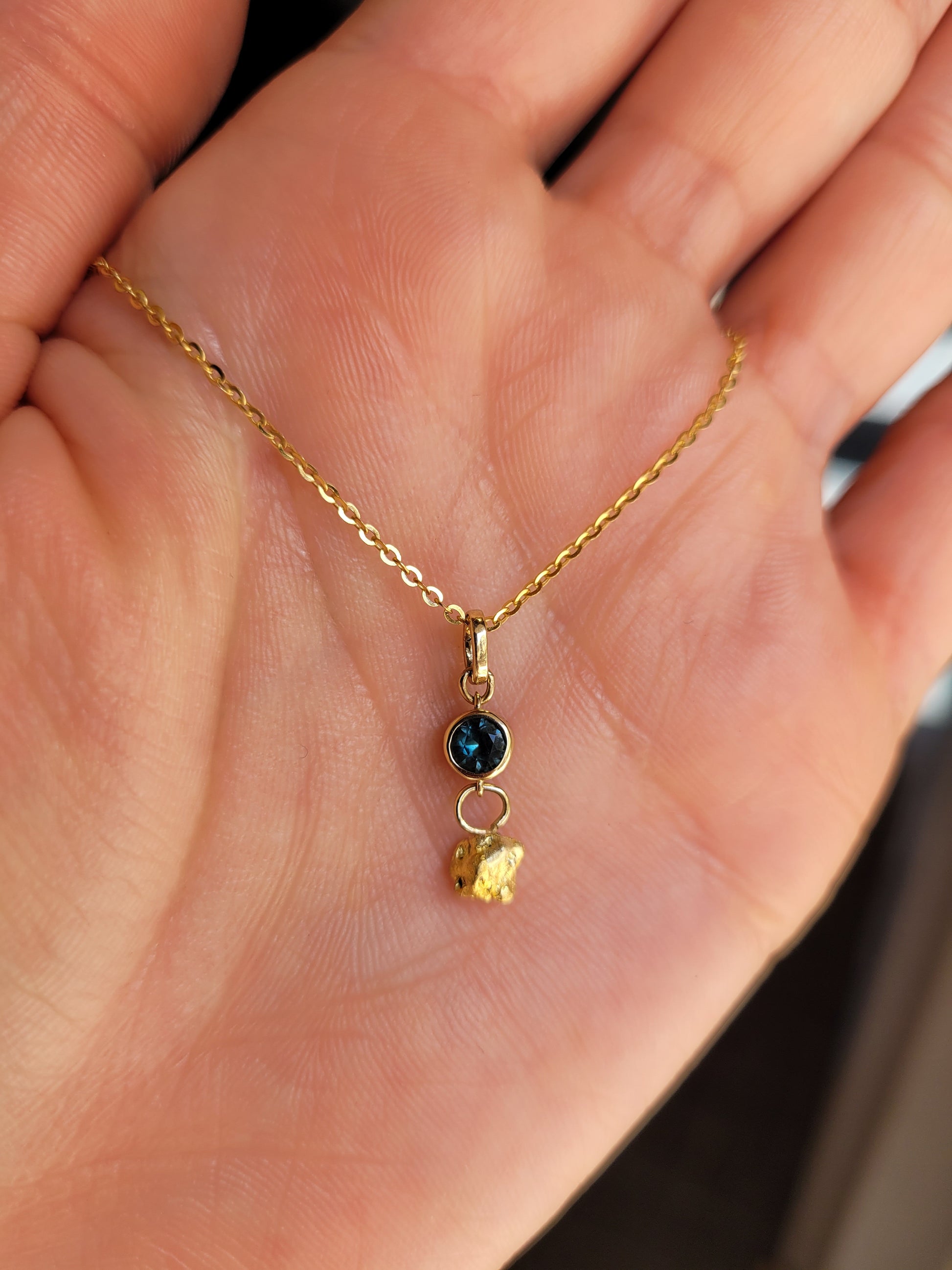photo on hand of sapphire and gold nugget pendant