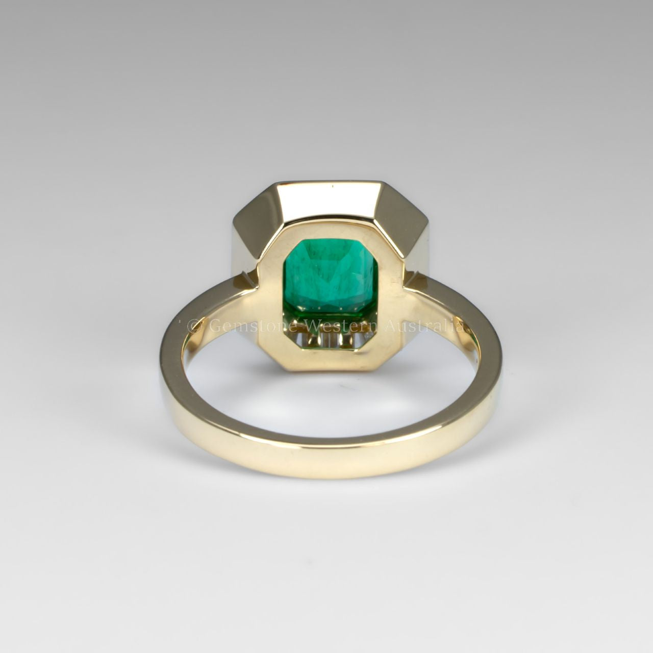 back view of Emerald Cut Colombian Emerald Ring with Baguette Diamond halo in white background