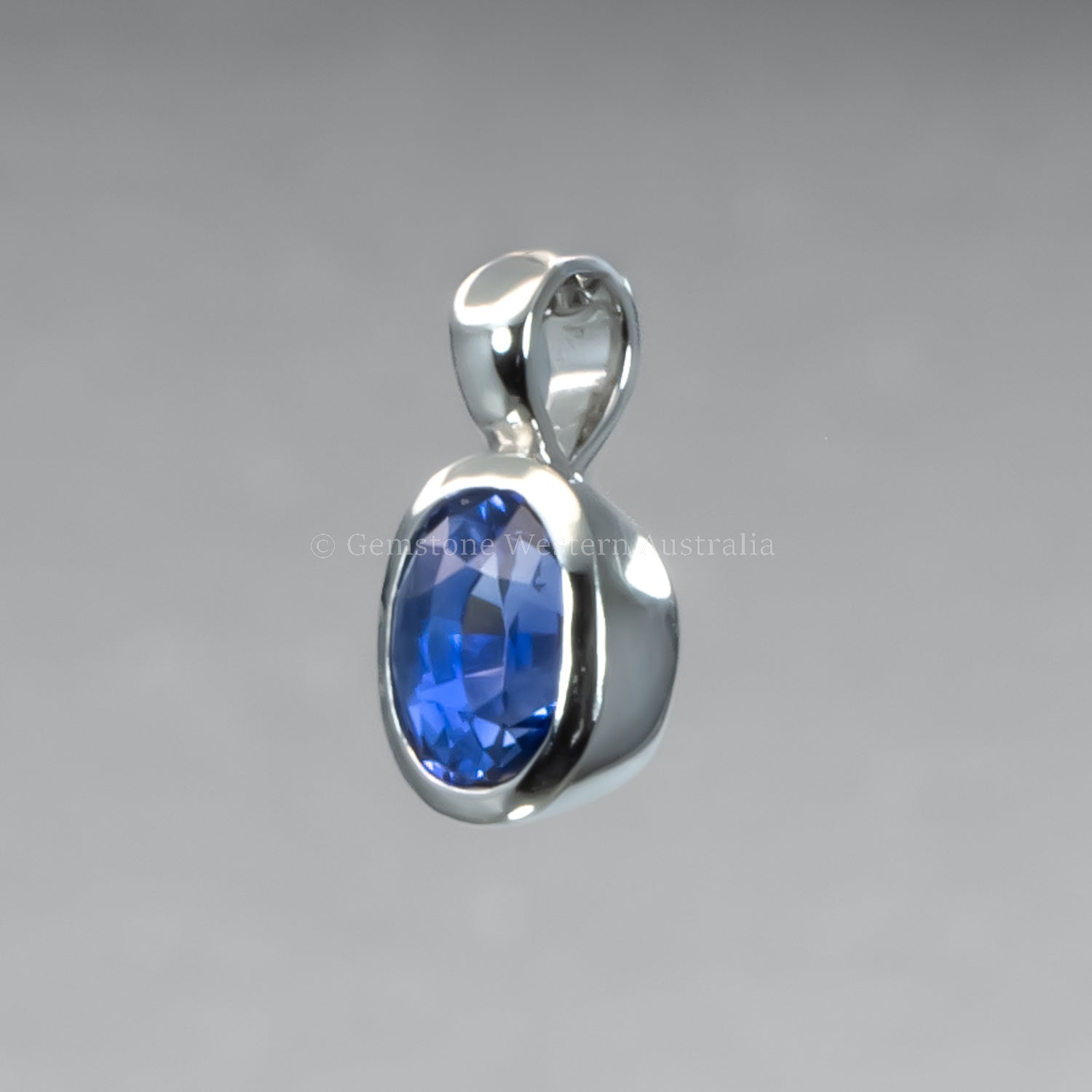side view of pendant with a blue gemstone on a gray background