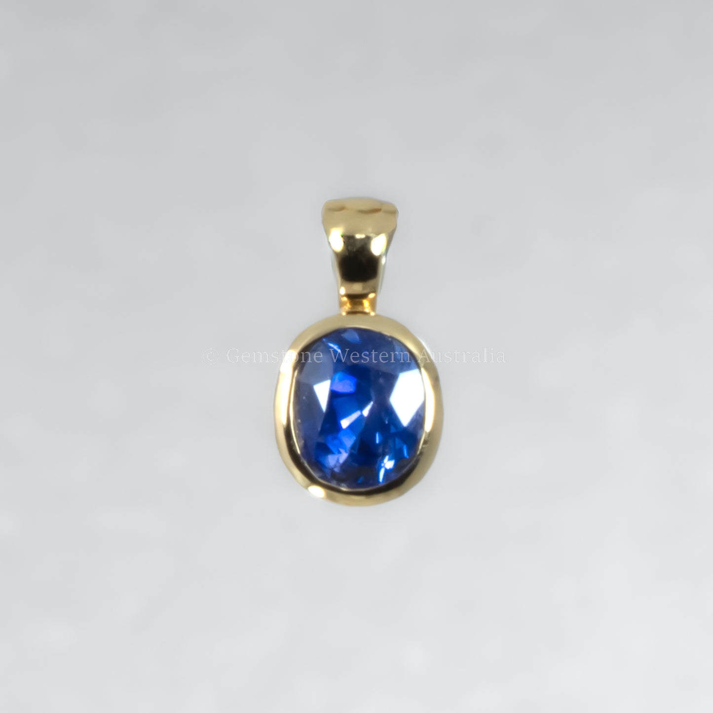 Gold pendant with a blue gemstone on a white background