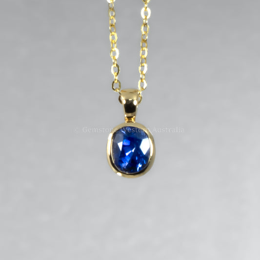 Gold necklace with a blue gemstone pendant on a gray background