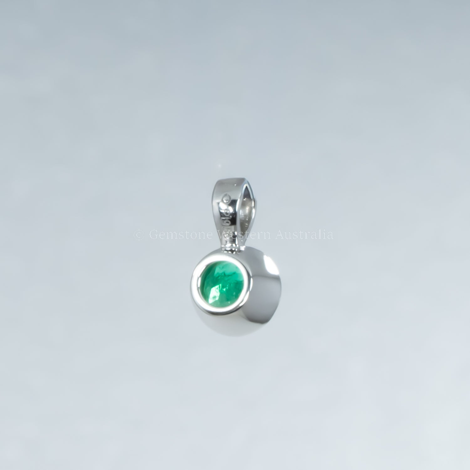 back view platinum pendant with a green gemstone on a light gray background