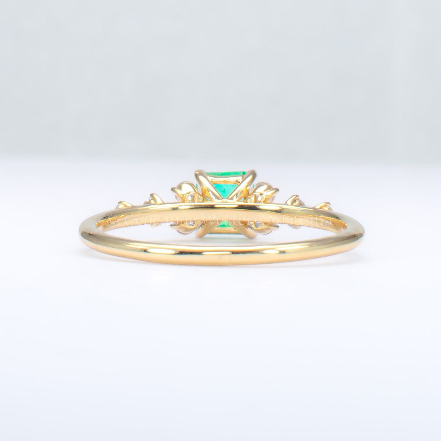 back view of Yellow gold ring with Colombian emerald and diamonds on gray background