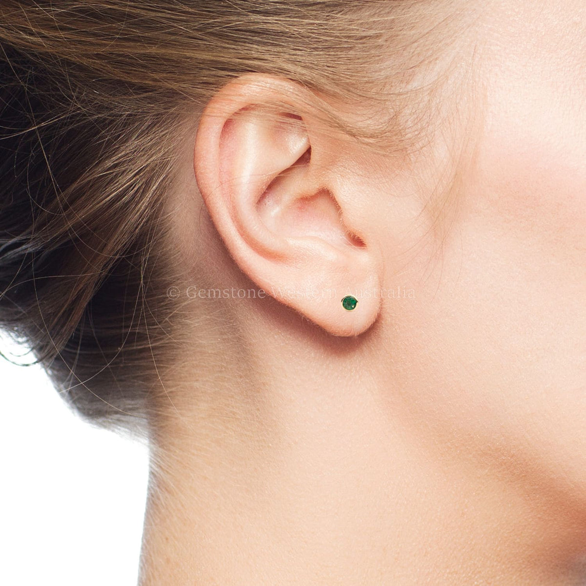 Close-up of an ear wearing a green gemstone