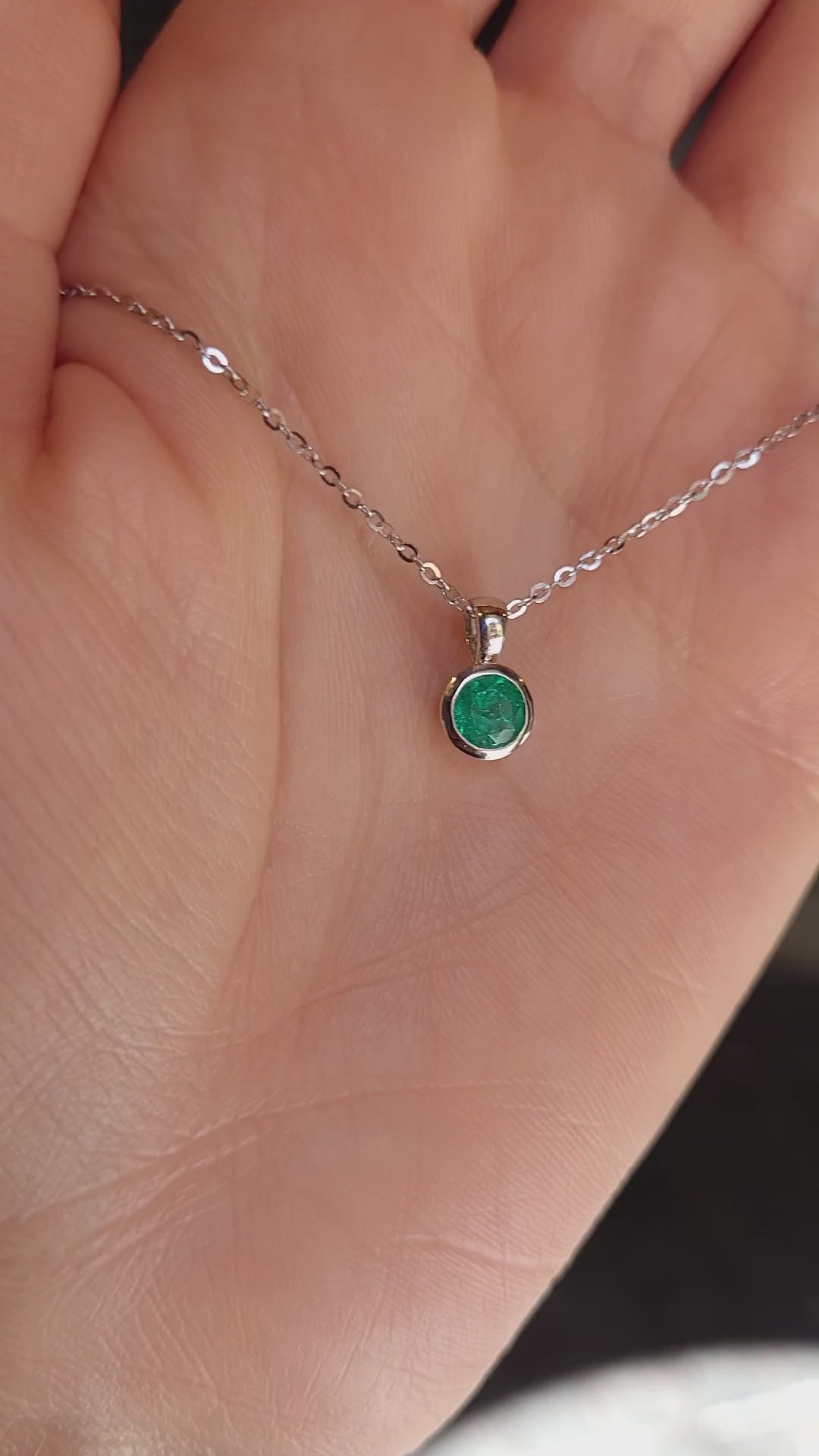 video of Platinum necklace with an emerald pendant held on hand