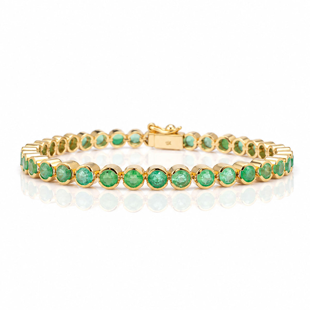 A yellow gold tennis bracelet with Colombian emeralds on a white background