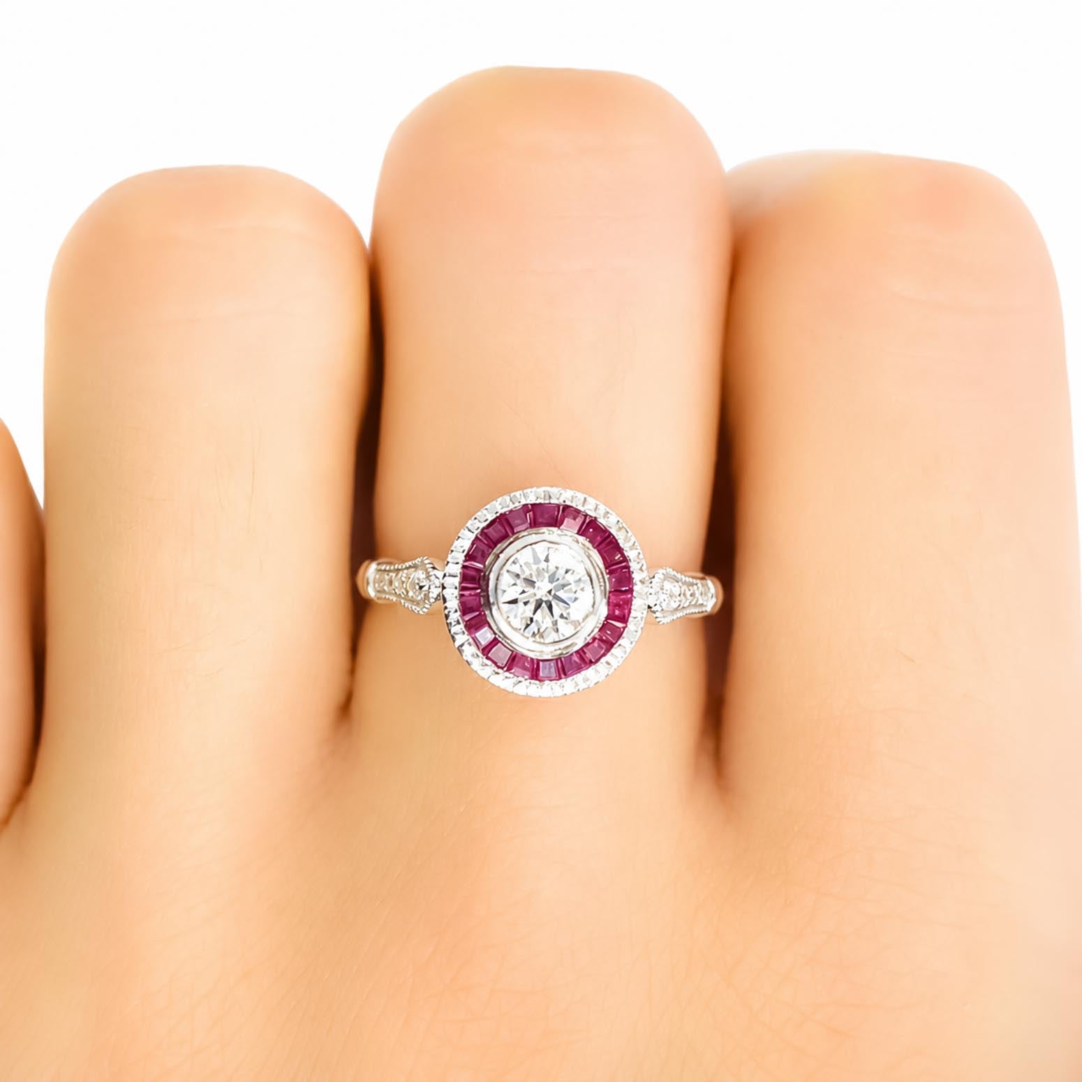 A close-up of a ring worn on a finger, featuring a round-cut diamond center stone surrounded by a halo of custom-cut baguette rubies on a white gold setting.