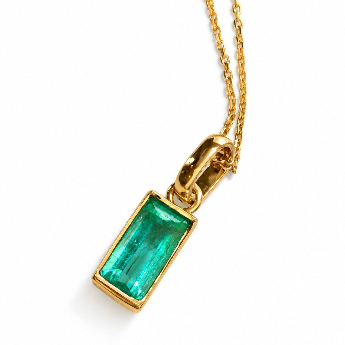 Bezel-set Colombian emerald pendant in 18K yellow gold, angled view