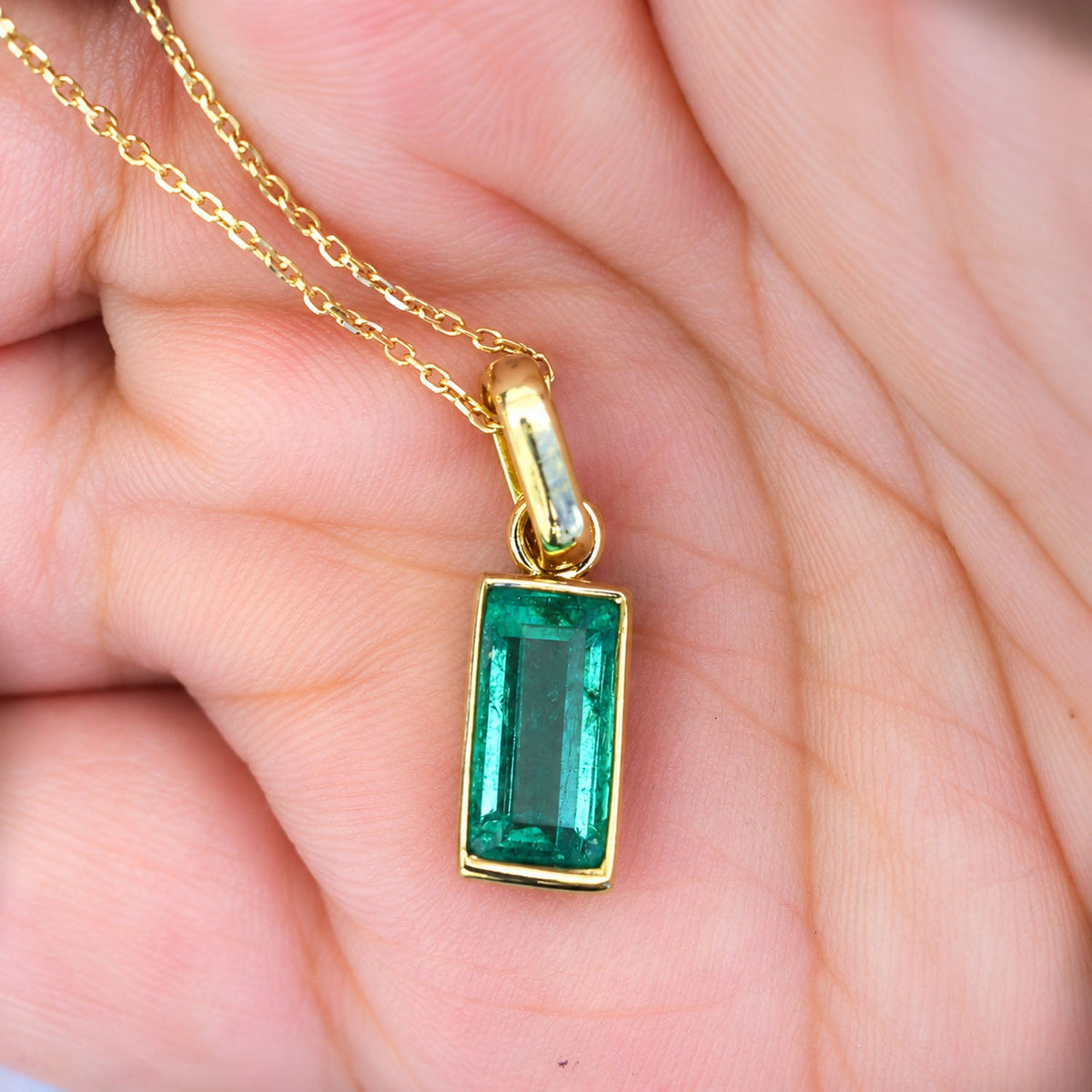 2.32 ct emerald pendant held in the hand to show its scale