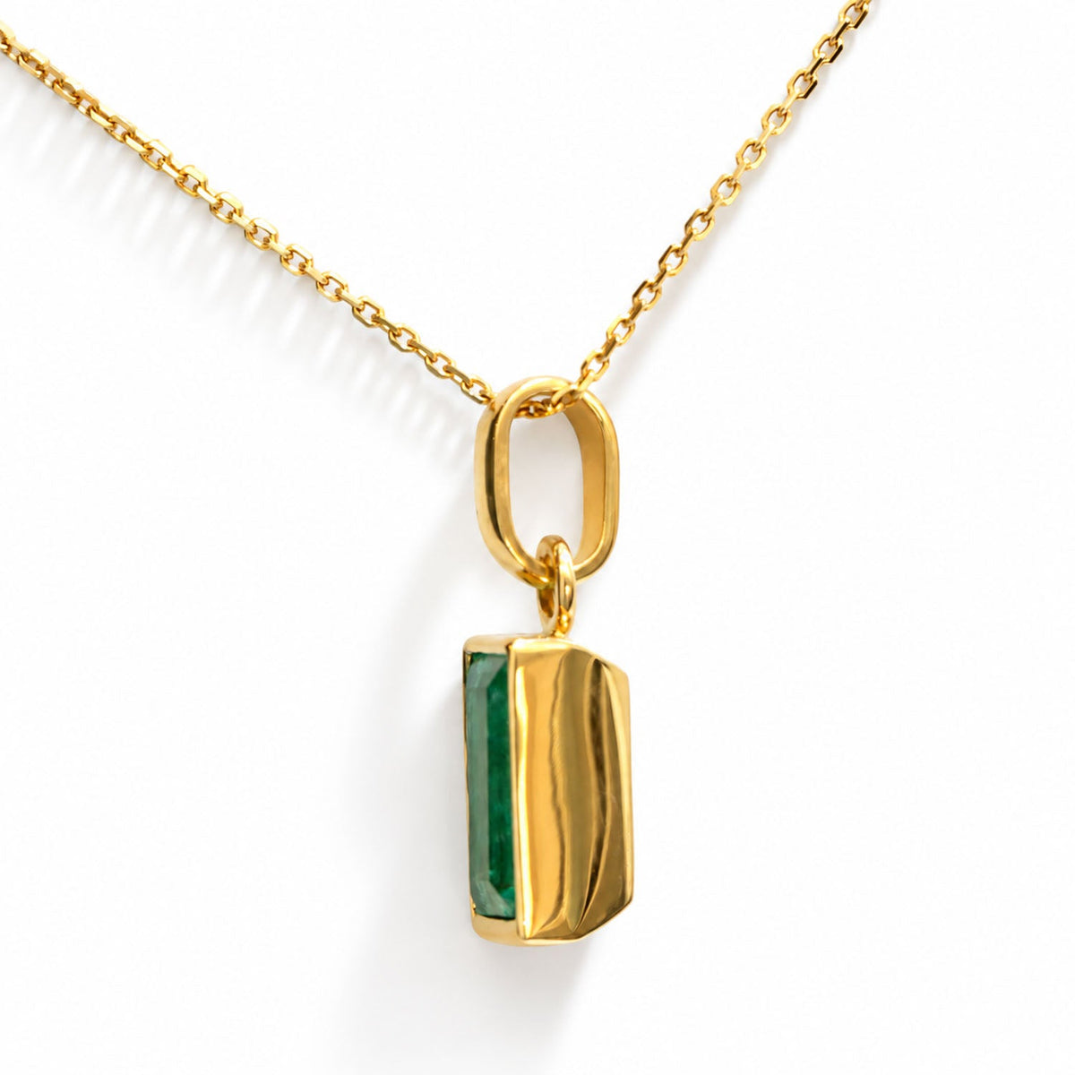 Side profile of the emerald pendant showing the gold bezel and bail