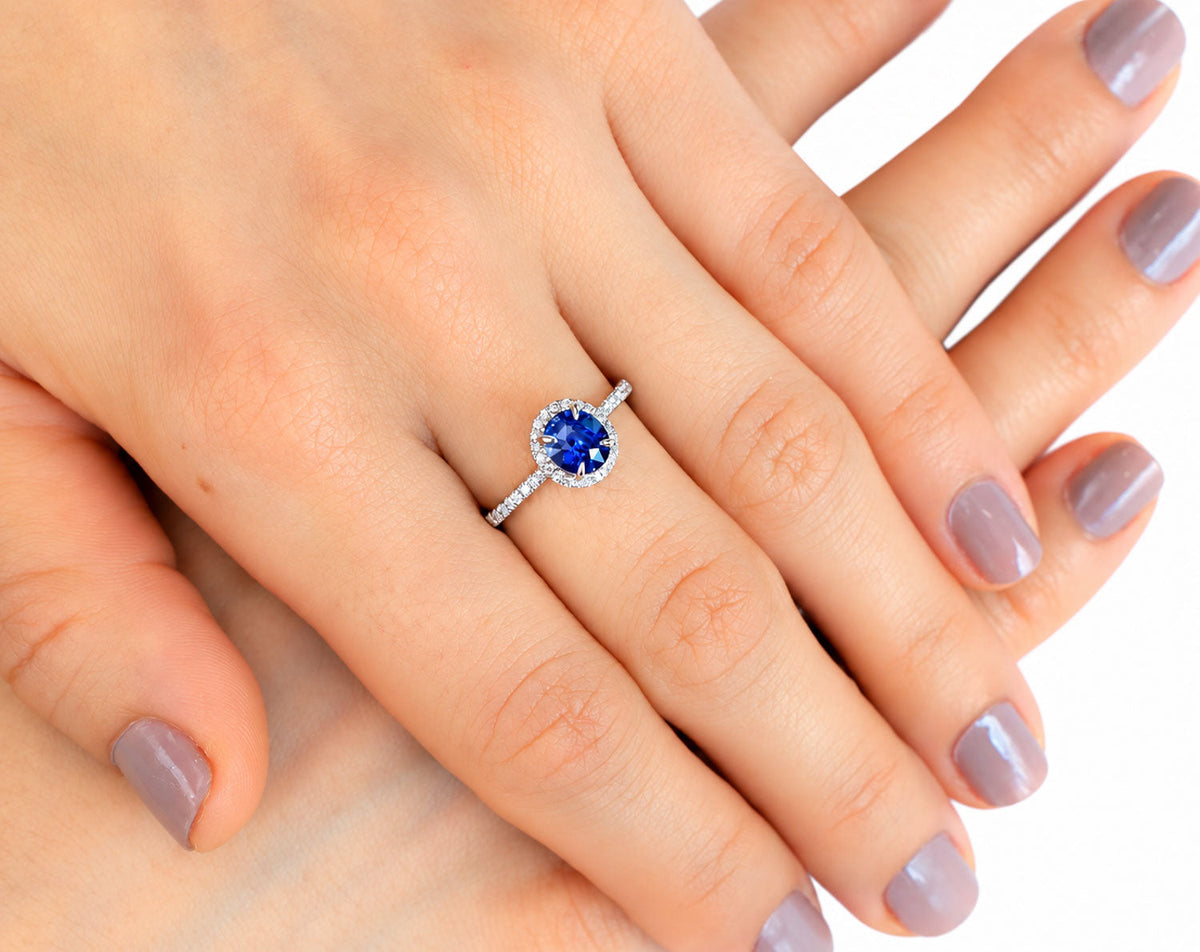 Blue sapphire halo ring worn on the hand, close view