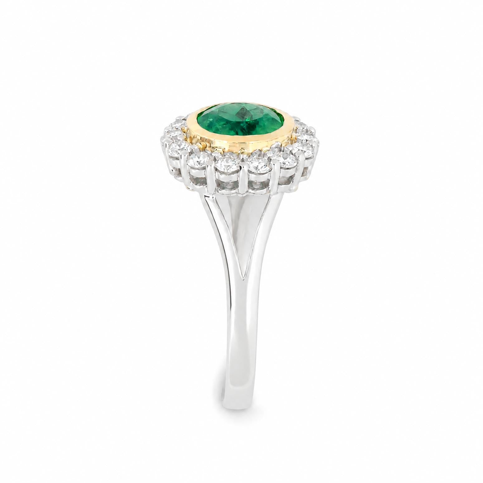 A yellow gold and white gold ring featuring a round Colombian emerald center stone surrounded by a halo of round diamonds, set on a polished white gold band.