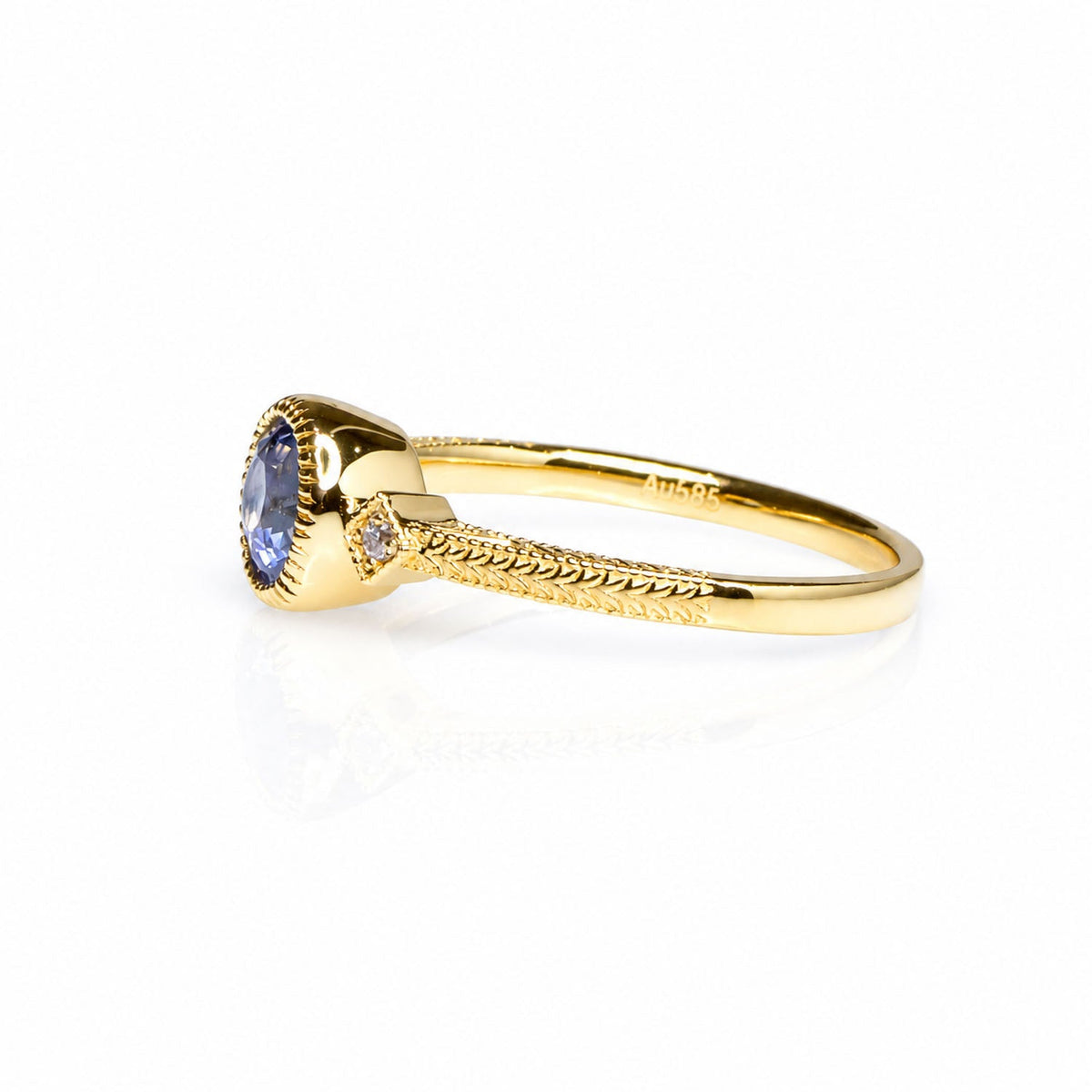 Side profile of the sapphire ring showing its engraved gold band