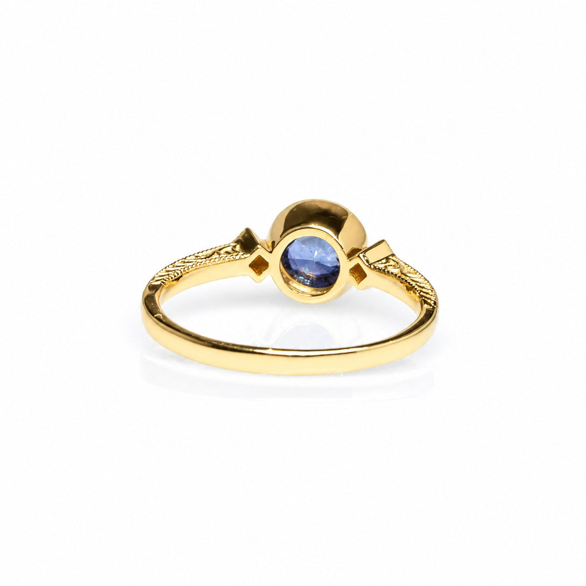 Angled view of the bezel-set sapphire in its 14K gold setting