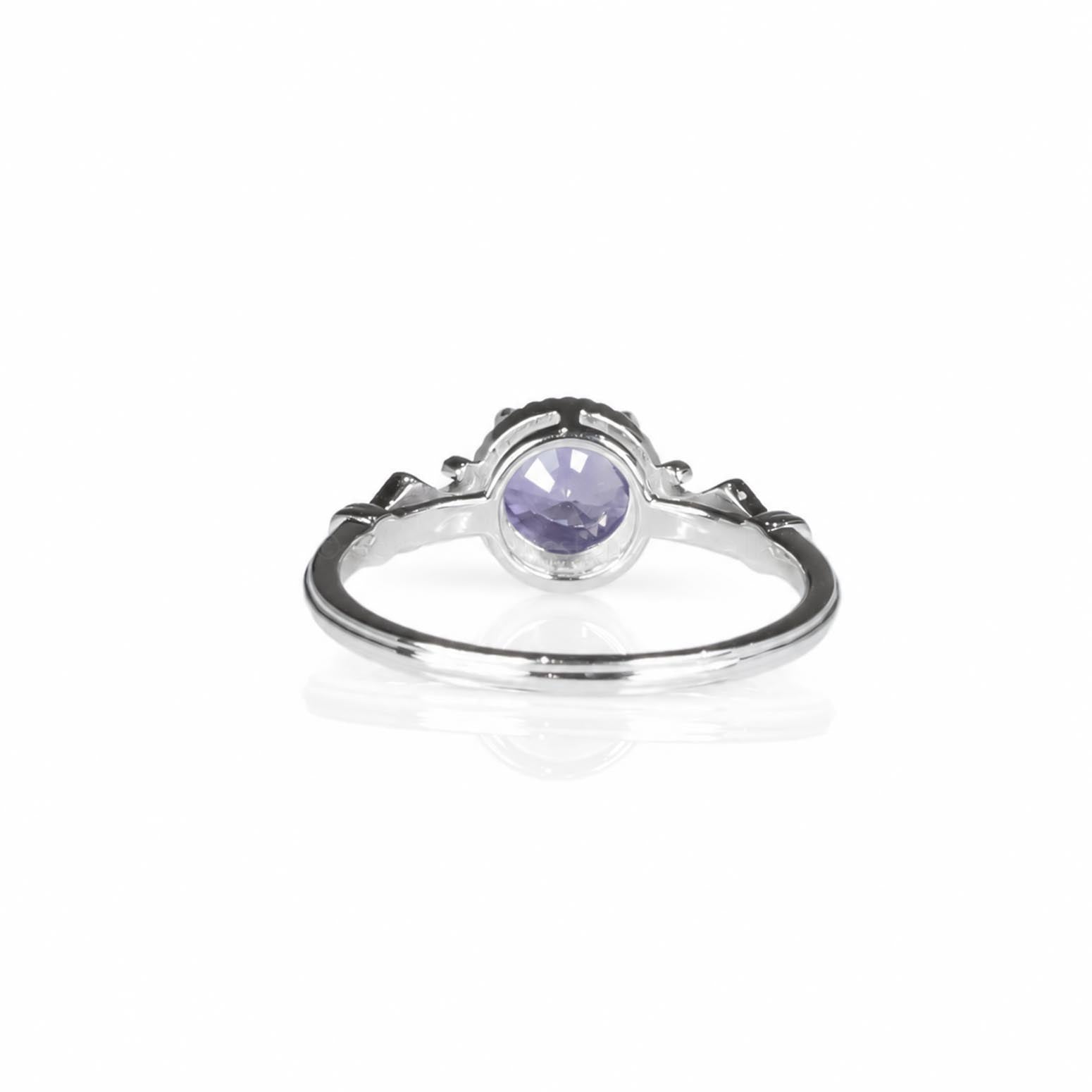 Back view of a platinum ring featuring a round, violet sapphire gemstone, shown on a clean white background with a soft reflection below.