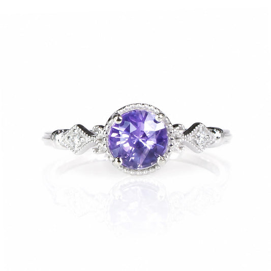 A white gold diamond ring featuring a round purple sapphire center stone in a halo setting, with diamond-accented shank on a white background.