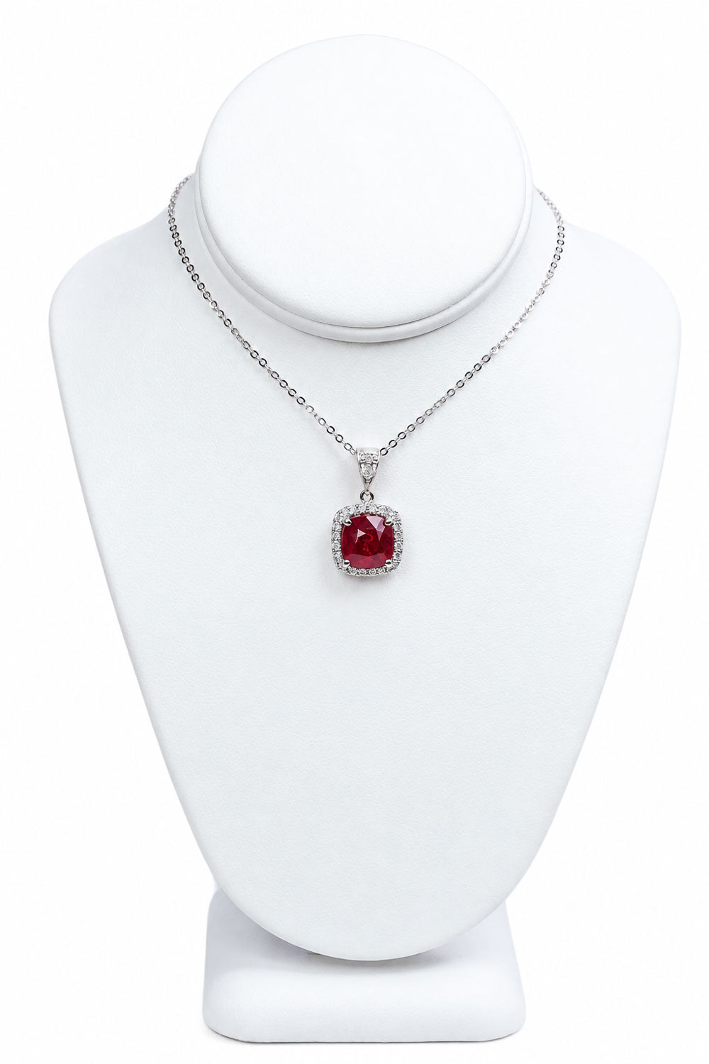Ruby halo pendant displayed on a jewellery bust with its white gold chain