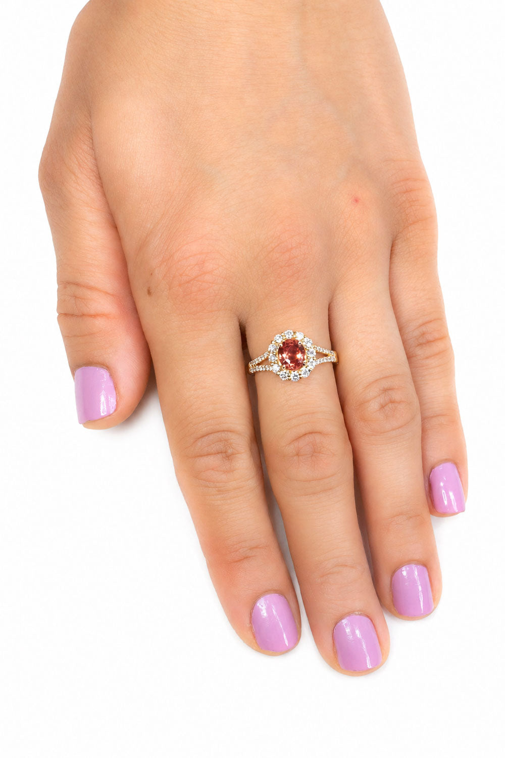 Padparadscha sapphire halo ring worn on the hand