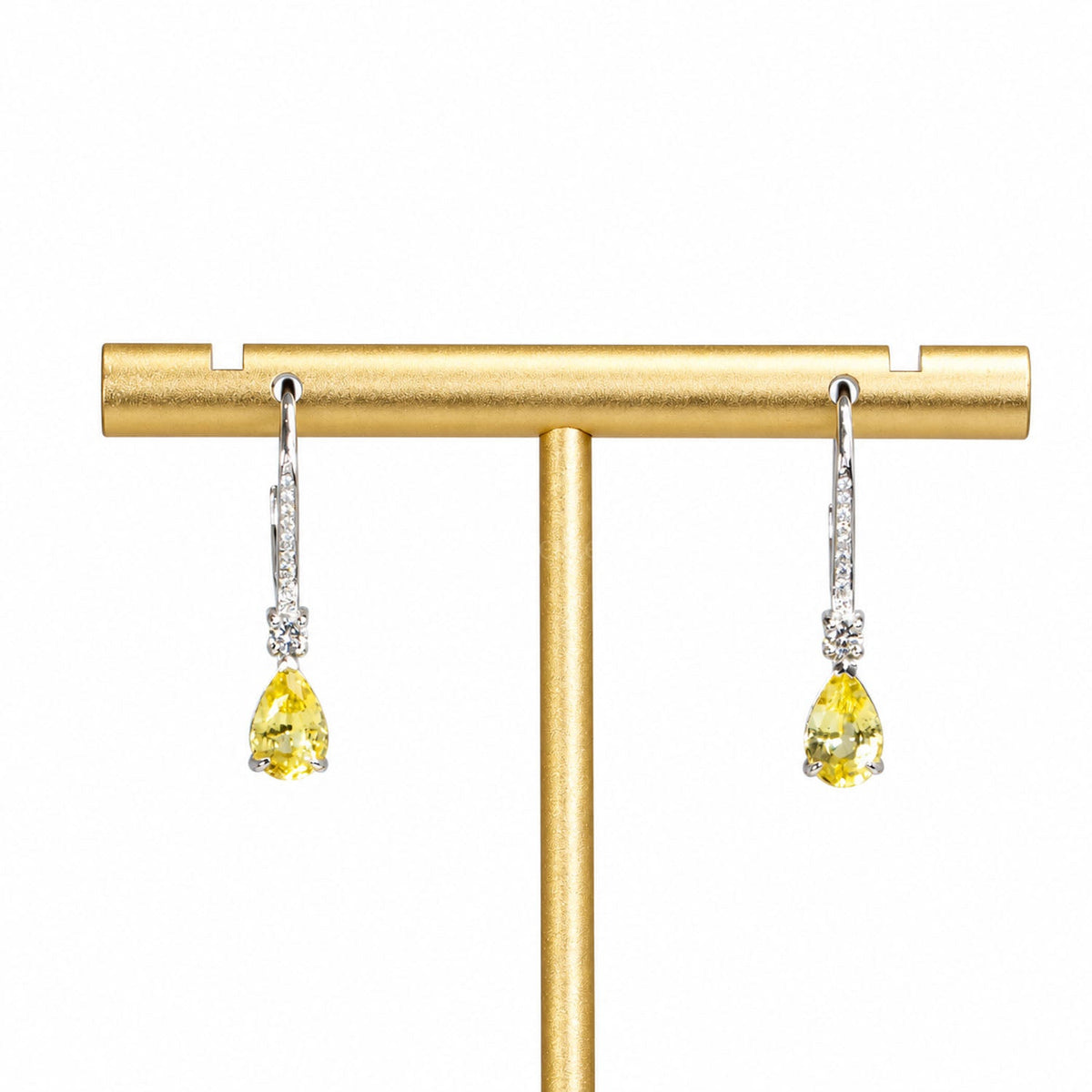 Unheated yellow sapphire and diamond drop earrings on a display stand