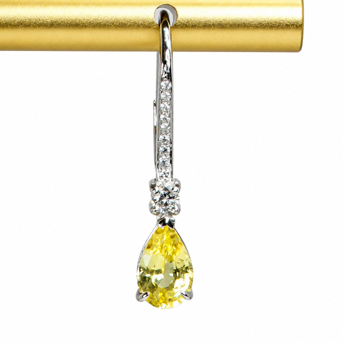 Pear-cut yellow sapphire suspended below a round diamond, close view