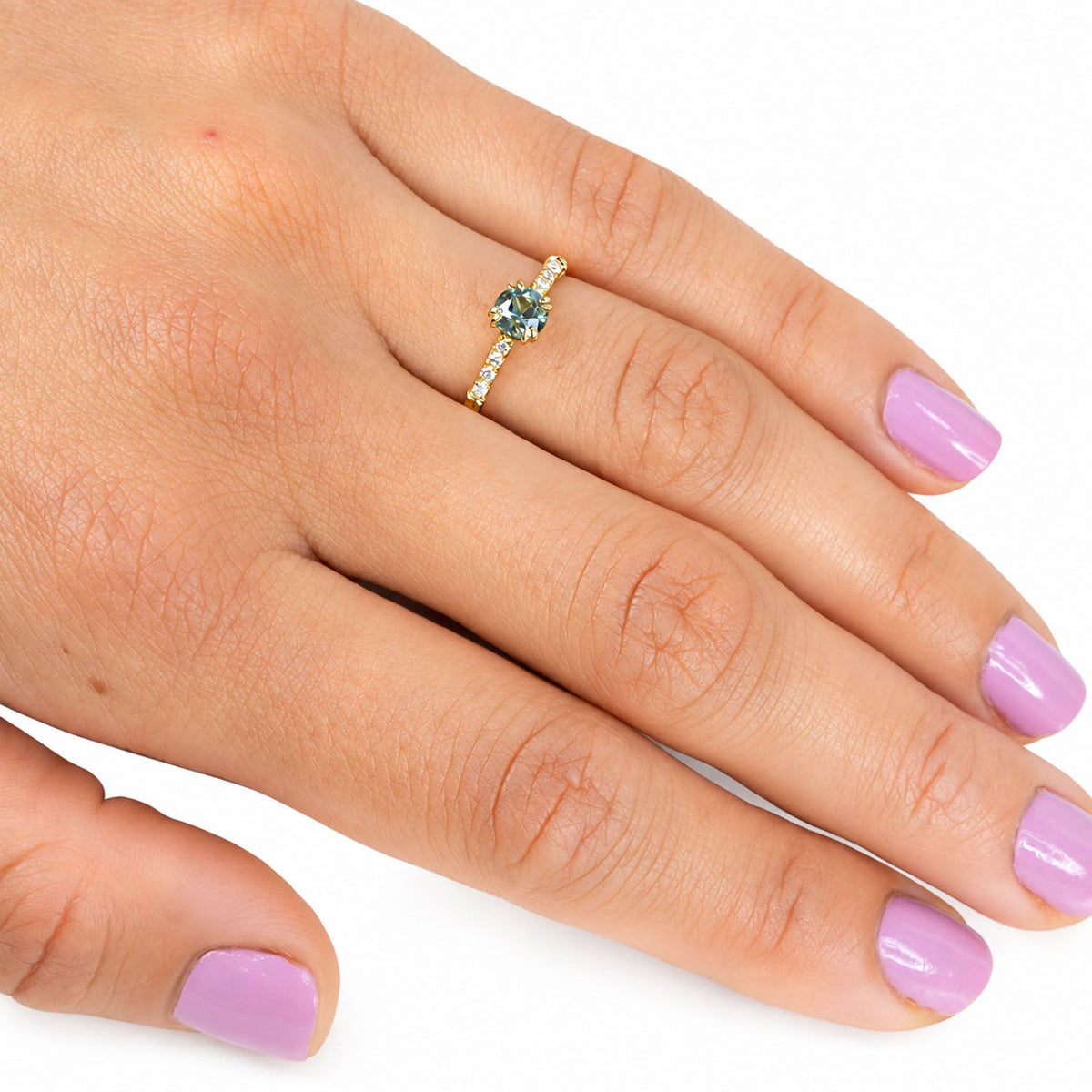 Teal sapphire and diamond ring worn on the hand