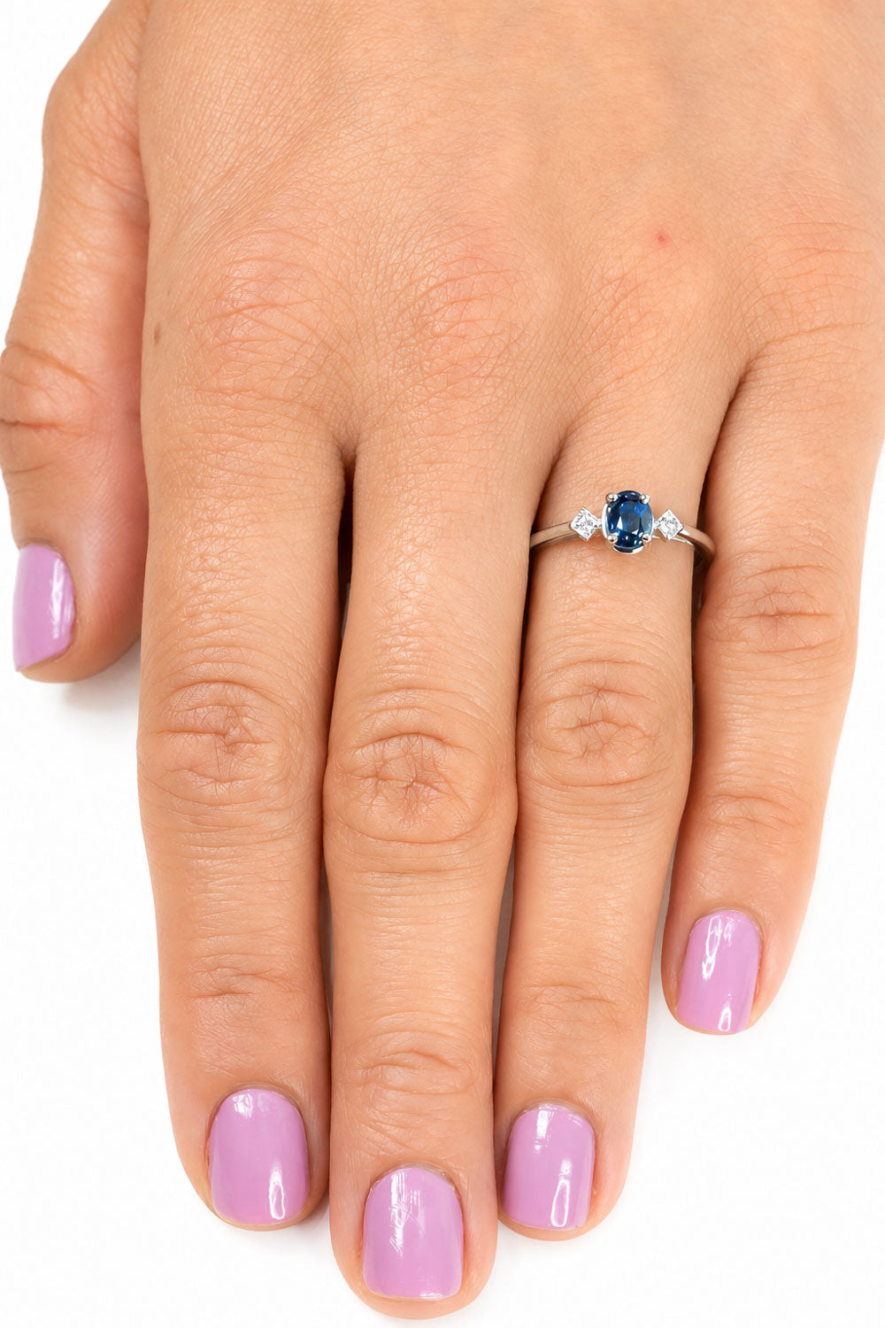 Oval teal sapphire ring worn, hand resting