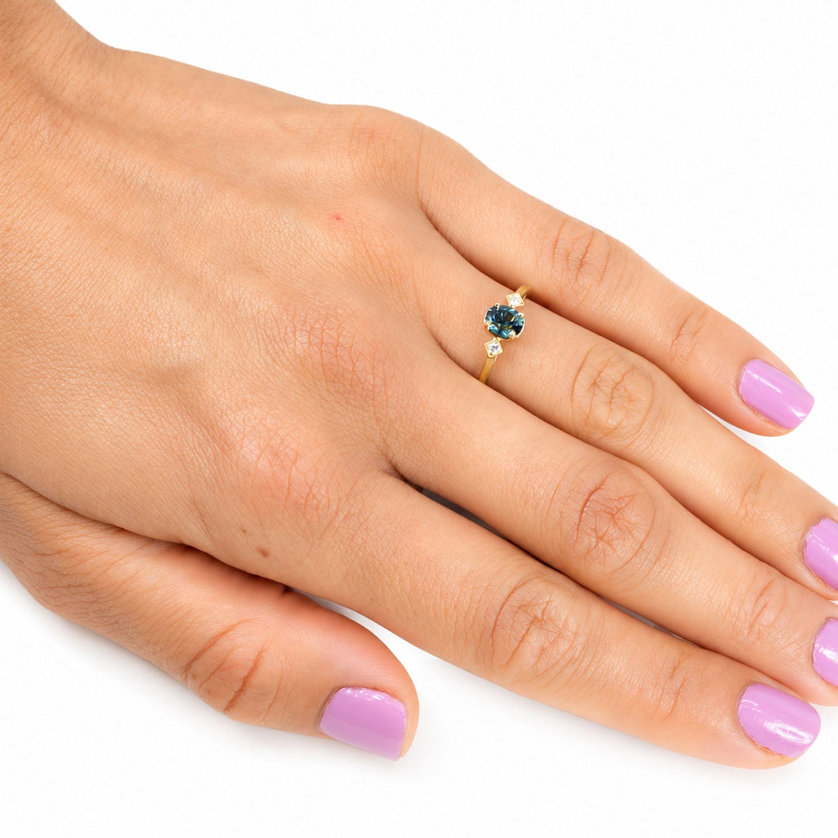 Teal sapphire and diamond ring worn on the hand