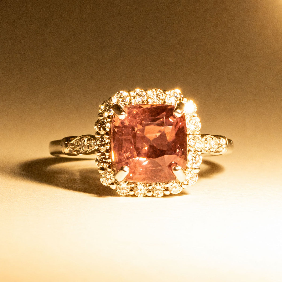 The same alexandrite halo ring under warm light, showing its pink colour change
