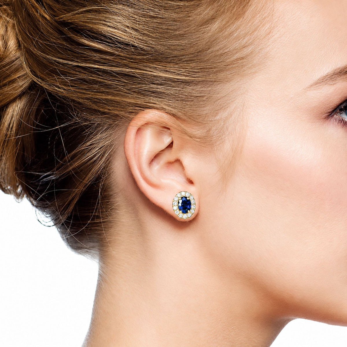 Blue sapphire halo stud earring worn on the ear