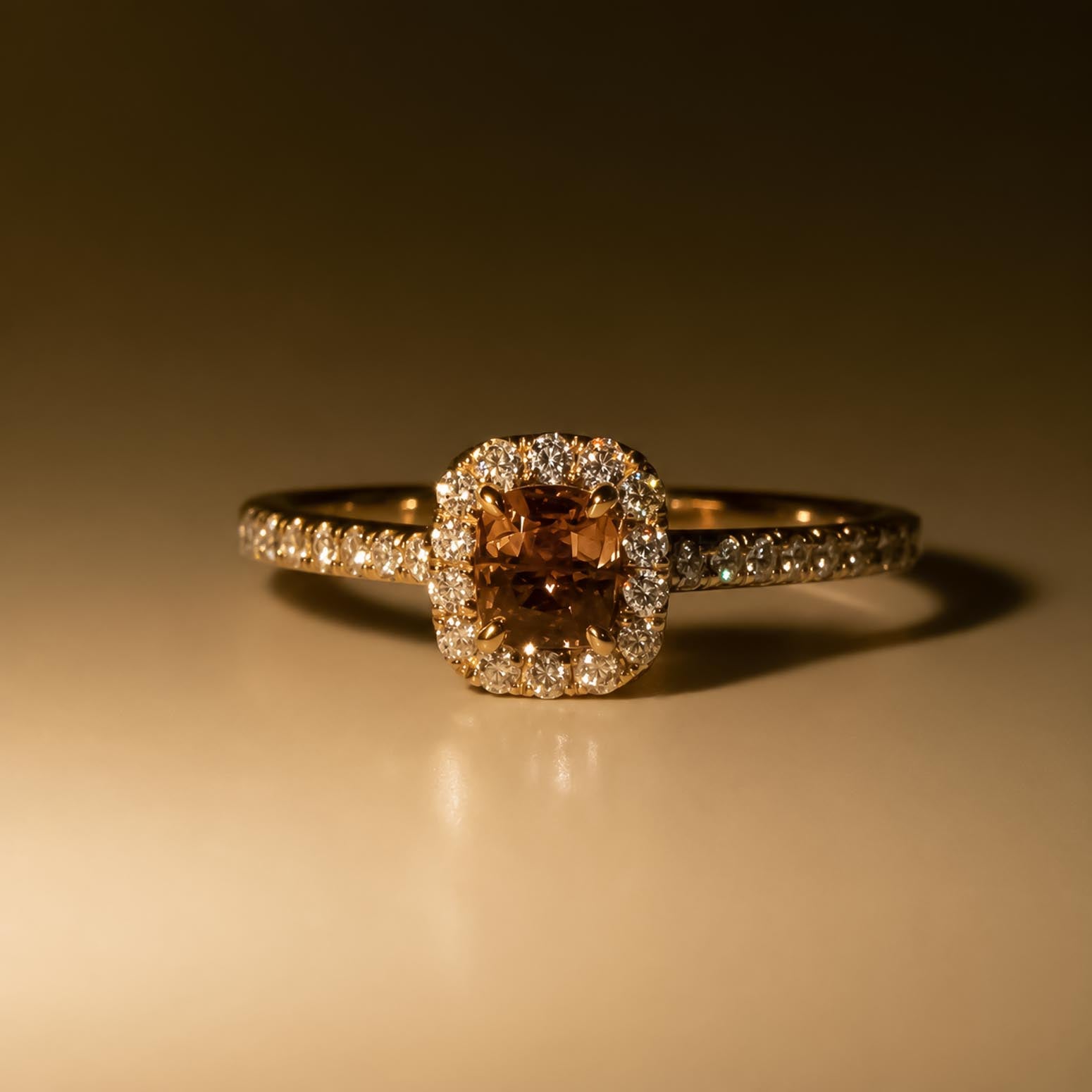 A rose gold halo ring featuring a cushion-cut alexandrite with a halo of diamonds and diamond side stones, photographed on a warm incandescent lighting and reflective surface.