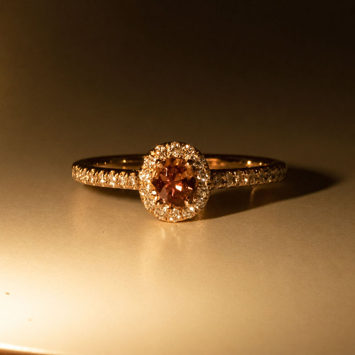 The same alexandrite halo ring under warm light, showing its pink colour change