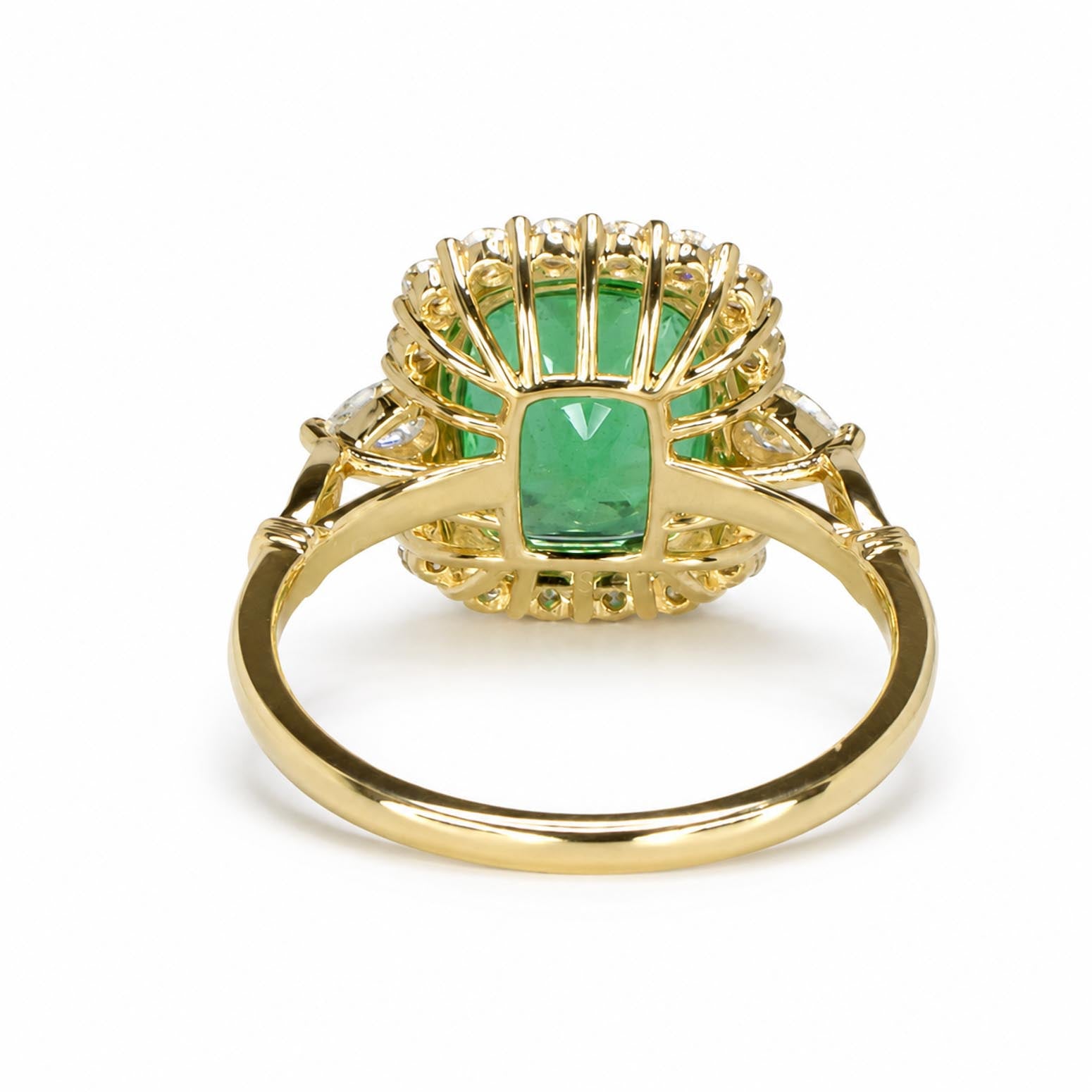 Back view of a yellow gold ring featuring a central Colombian emerald surrounded by smaller round-brilliant cut diamonds in a scalloped setting, shown on a plain white background.