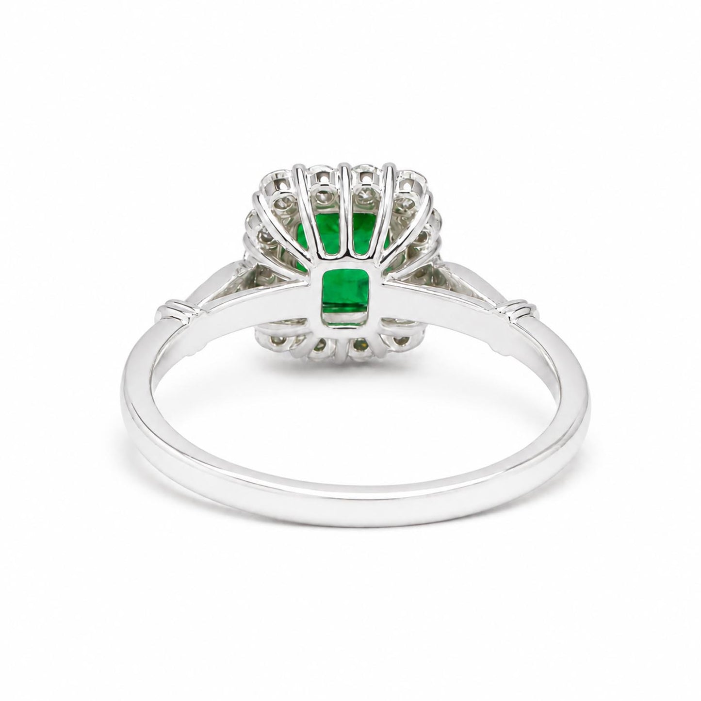Back view of a platinum ring featuring a central Colombian emerald and a surrounding cluster of round diamonds, set in a scalloped design on a polished platinum band.