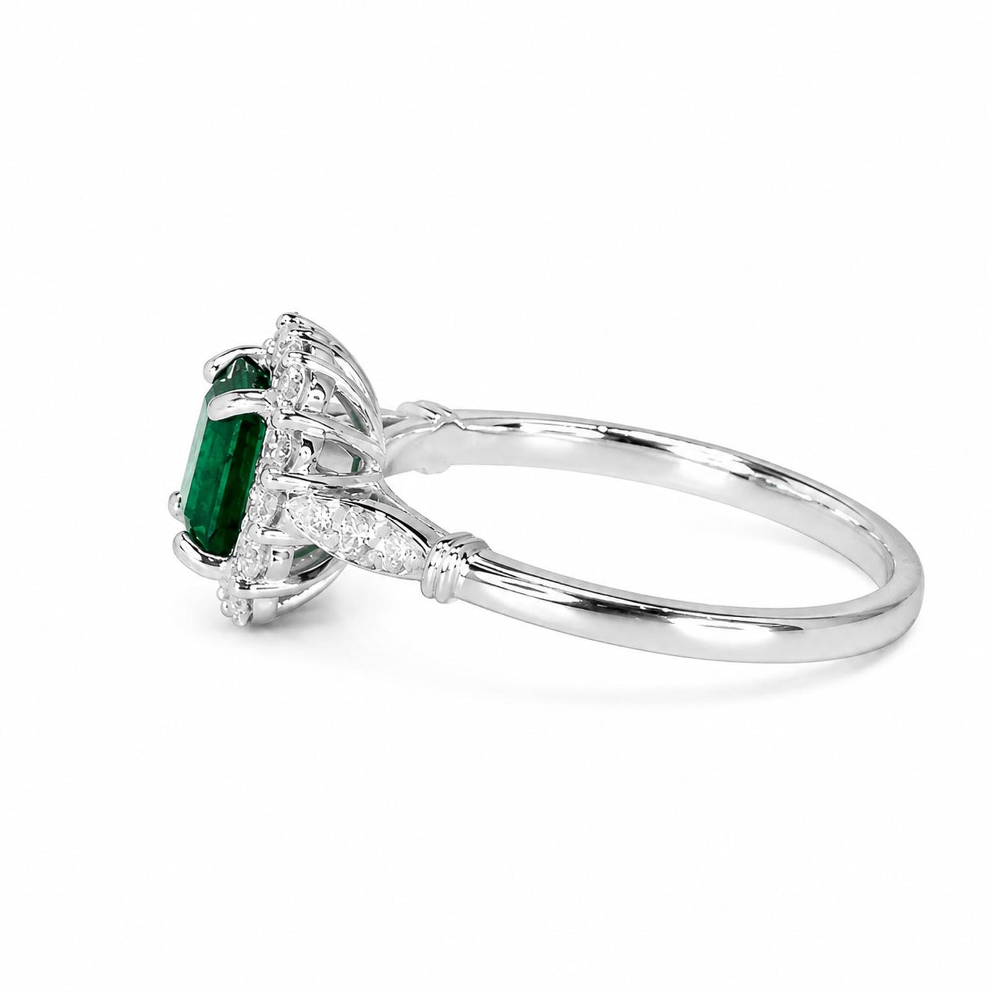 side view of a platinum ring featuring an emerald-cut Colombian emerald in a halo setting, accented with round diamonds along the shoulders, shown on a plain white background.