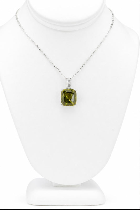 A platinum pendant holding a cushion cut green sapphire accented by two round brilliant cut diamonds on the bail shown on a jewellery display neck on a white background