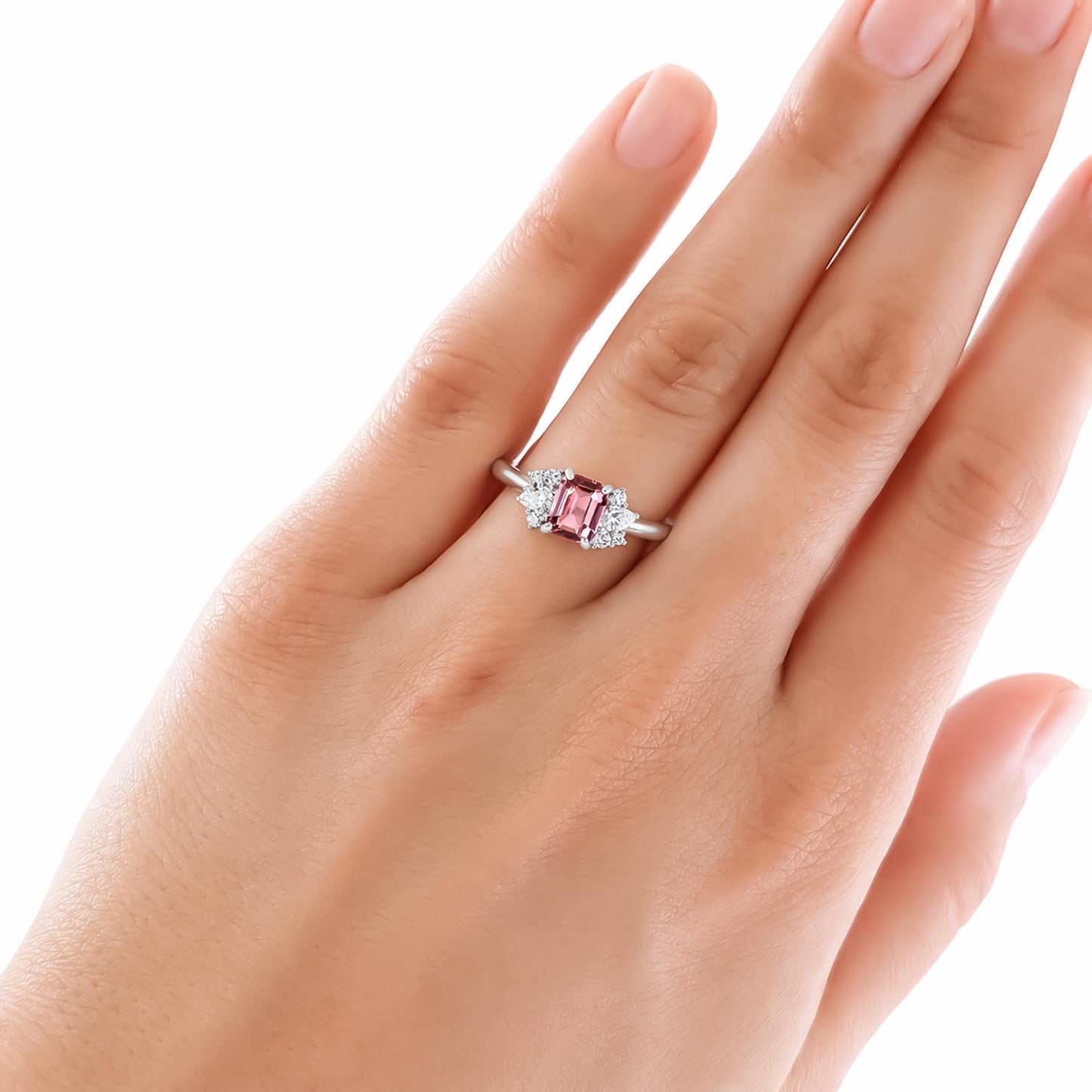 A close-up of a hand wearing a padparadscha sapphire and diamonds ring 