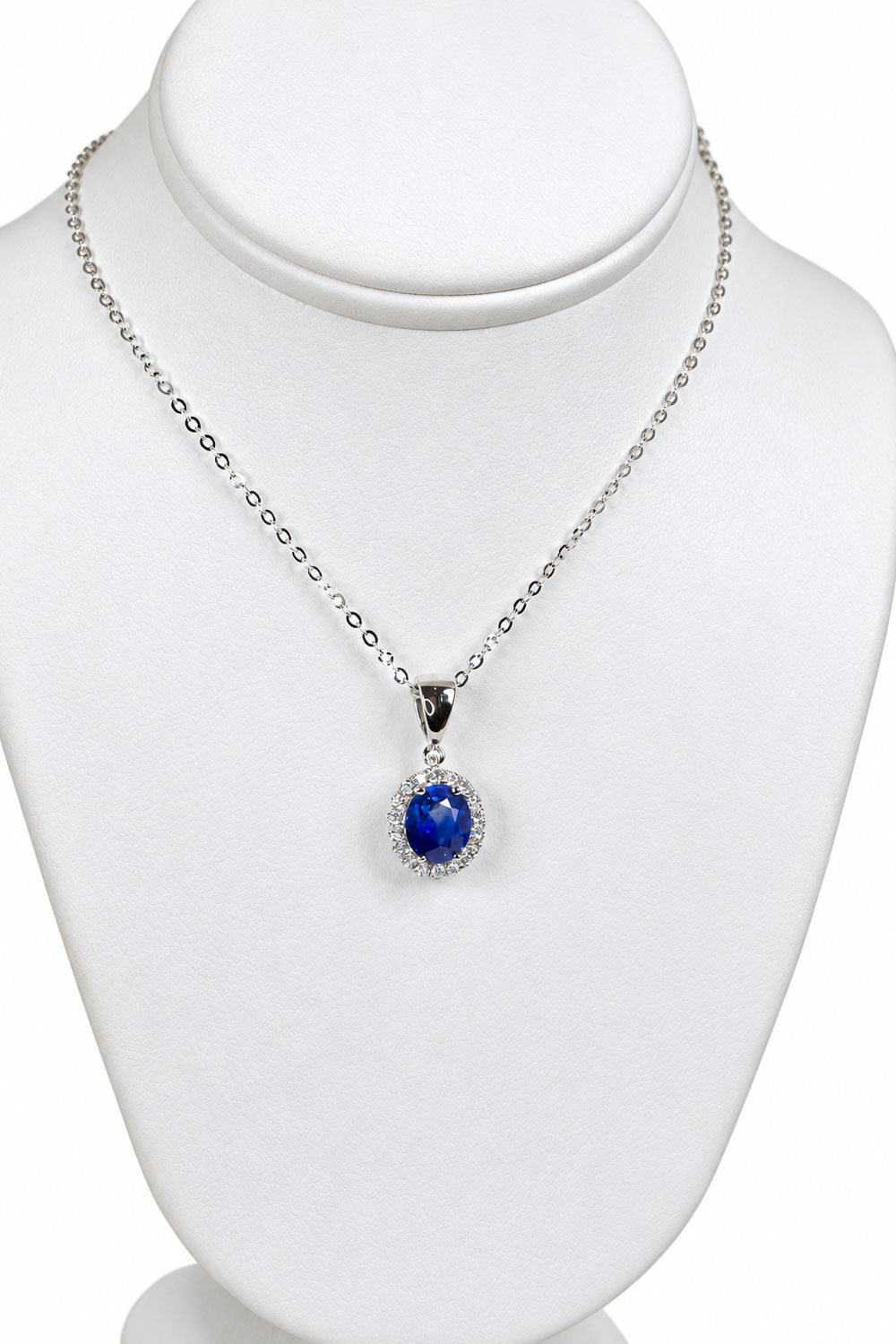 Sapphire halo pendant displayed on a jewellery bust with its chain