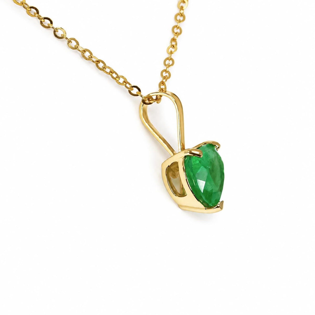 A gold pendant necklace featuring a faceted natural Colombian emerald heart-cut in a prong setting, suspended from a delicate gold chain against a plain white background.