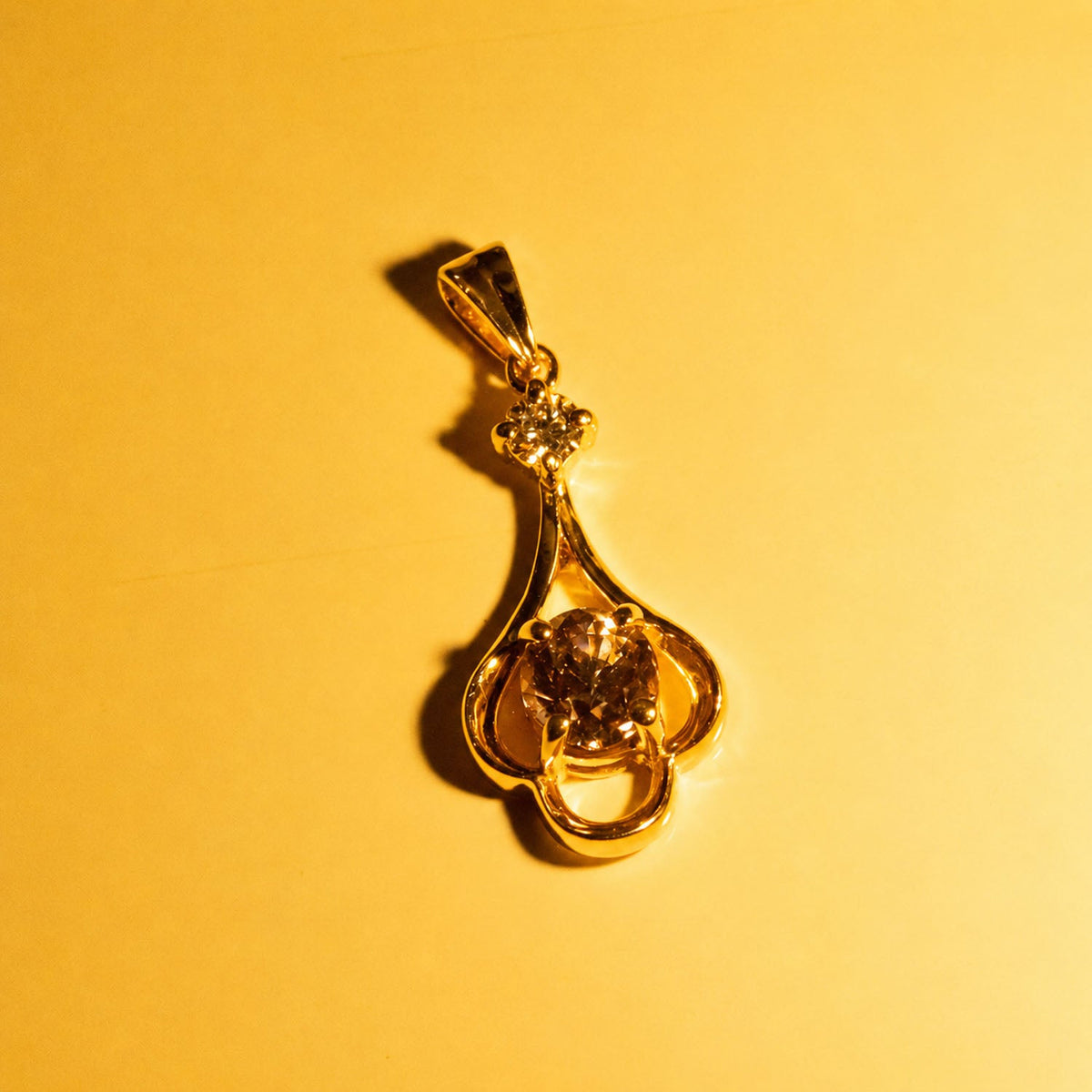 The same alexandrite pendant under warm light, showing its colour change