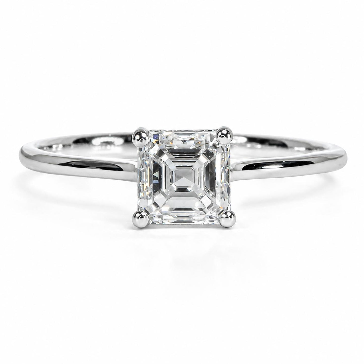 An emerald-cut diamond engagement ring in a polished platinum band, centered on a clean white background.