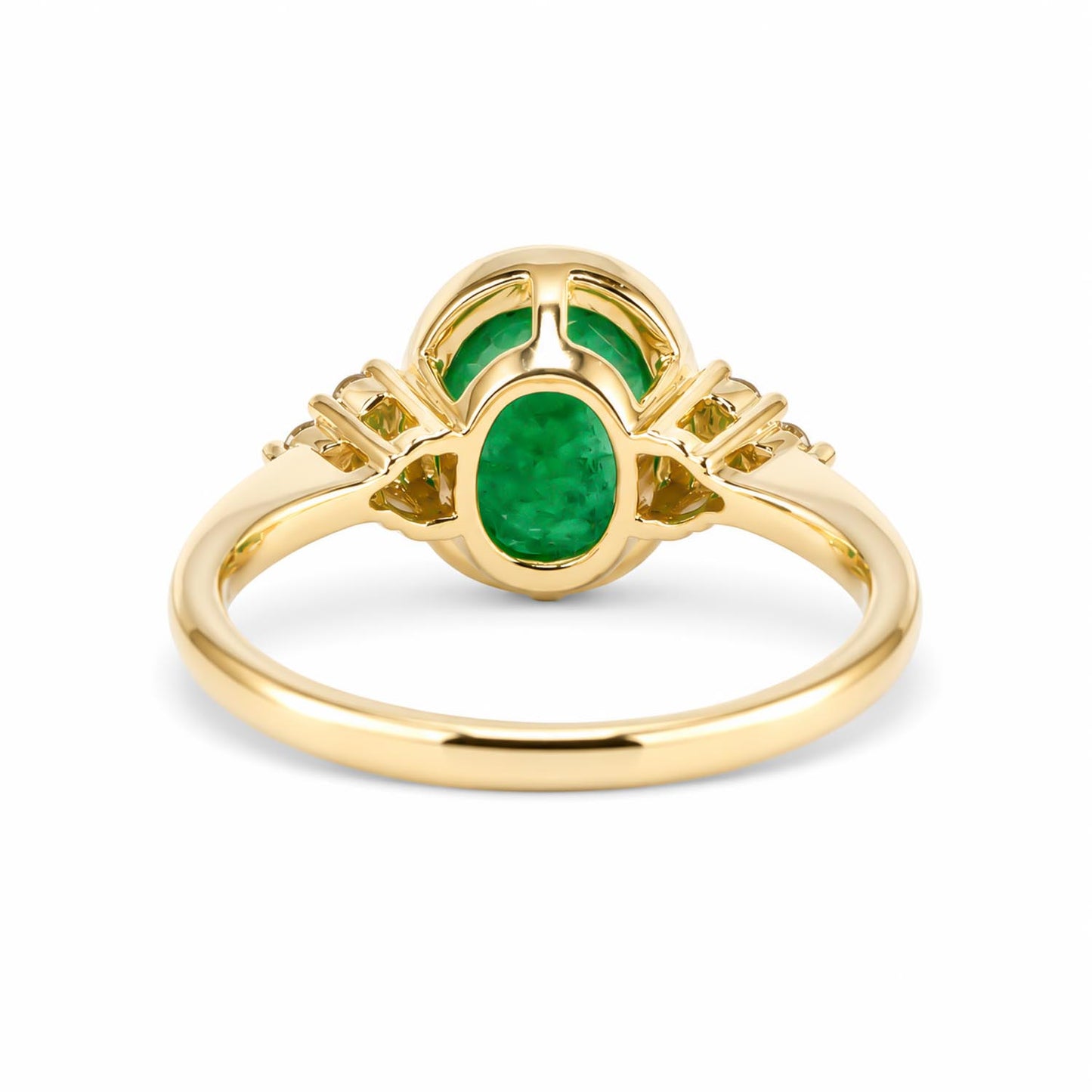 Back view of a yellow gold ring featuring a central oval-cut emerald and two smaller green stones behind it, set against a plain white background.