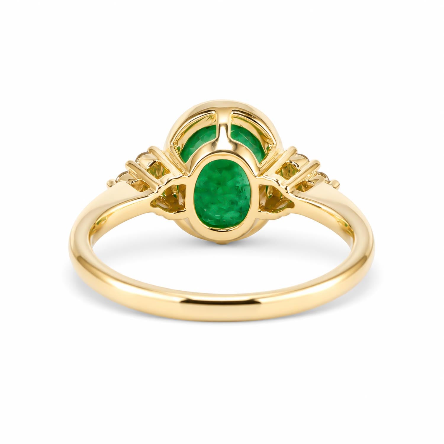 Back view of a yellow gold ring featuring a central oval-cut emerald and two smaller green stones behind it, set against a plain white background.