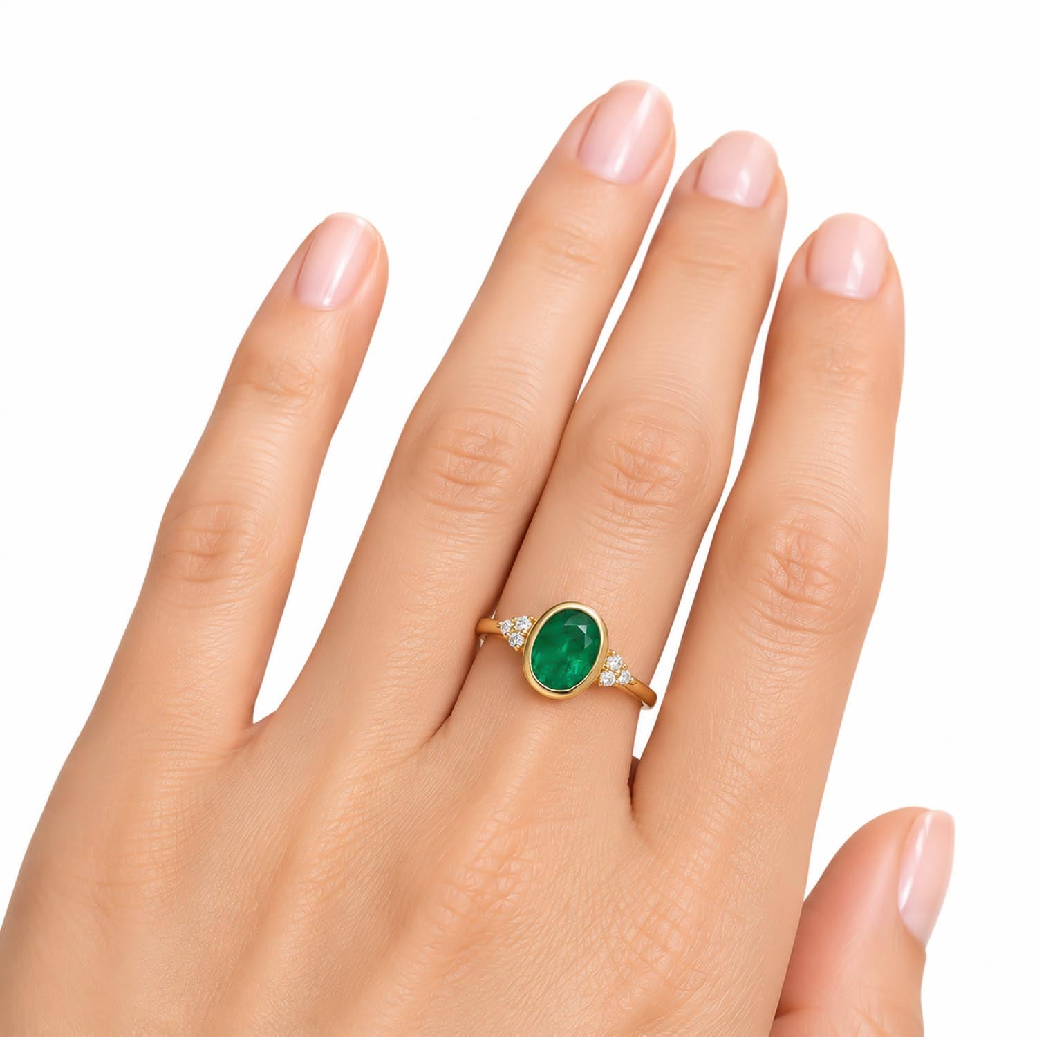 A gold ring with an oval-cut Colombian emerald center stone and small diamond accents on the band, shown worn on a hand against a white background.