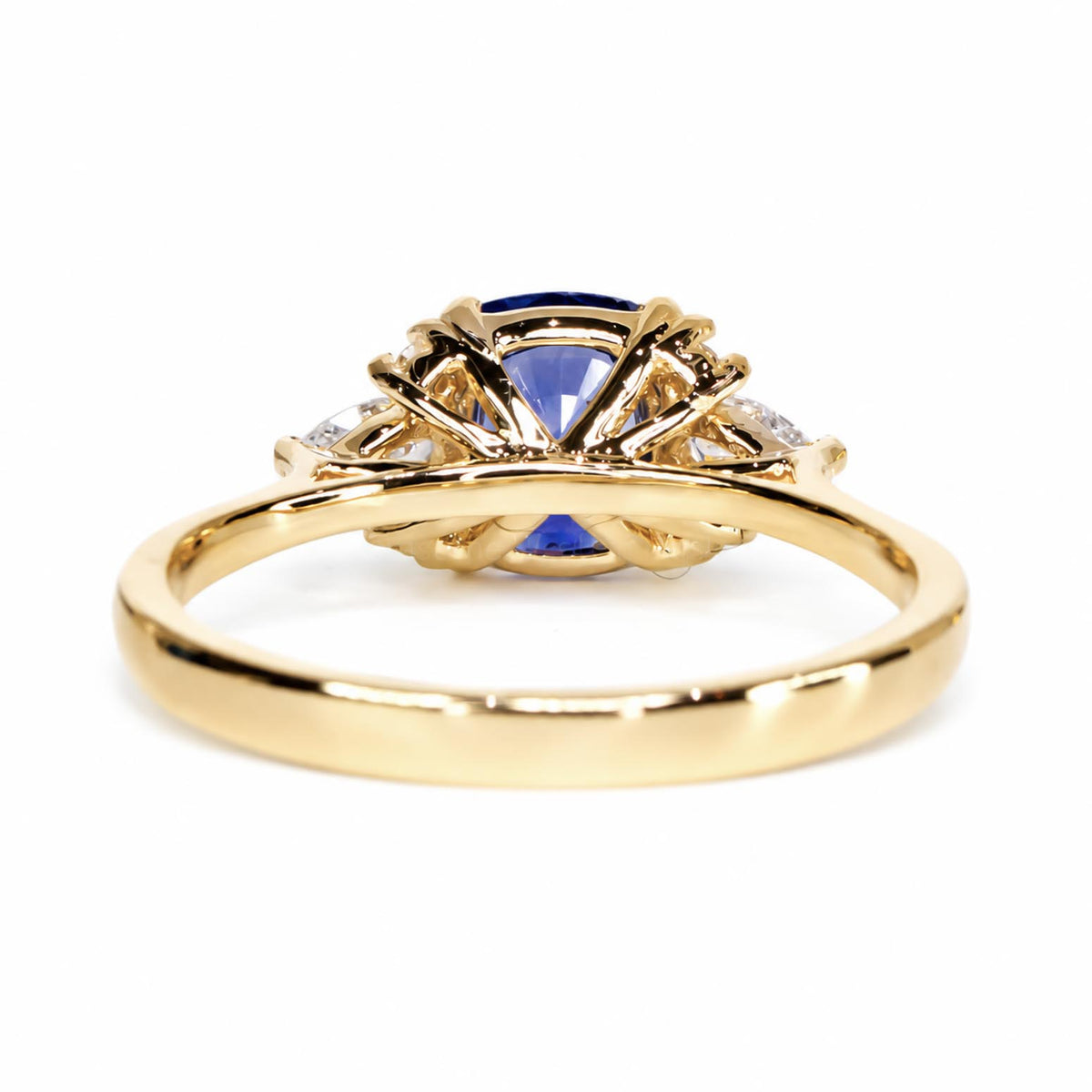 a 18K yellow gold sapphire ring shown from its back on a white background