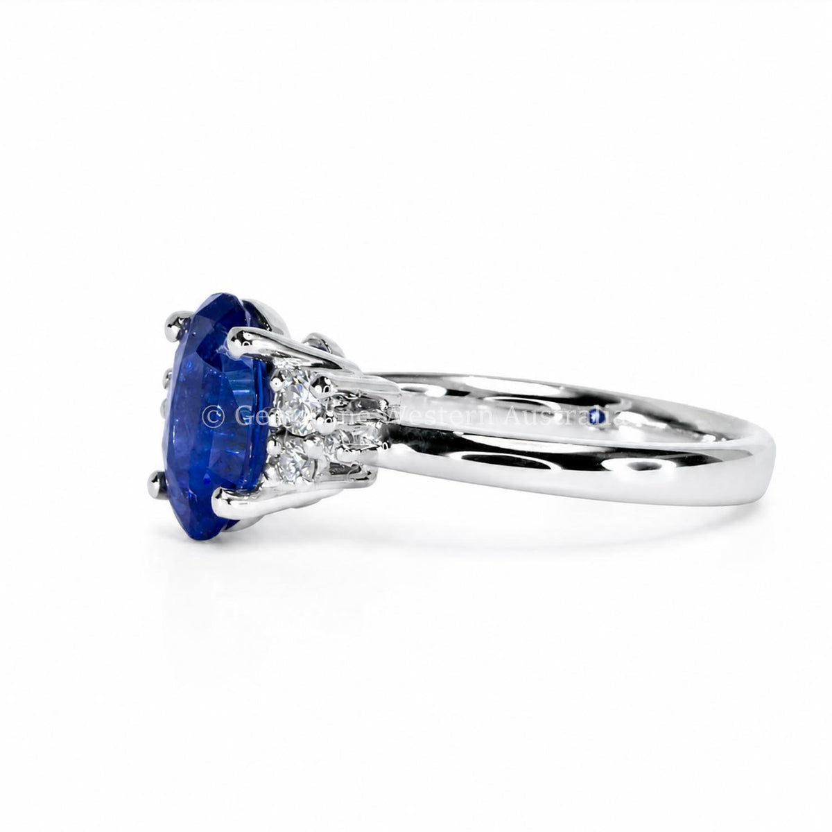 A platinum ring holding a natural oval blue sapphire as centre gemstone and a cluster of diamonds to its side 