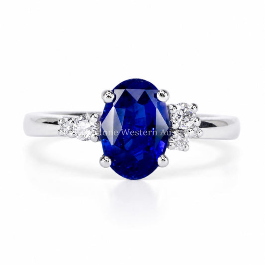 A platinum ring with a 2.1 carats oval cut royal blue sapphire with asymmetrically placed side diamonds in a platinum band 