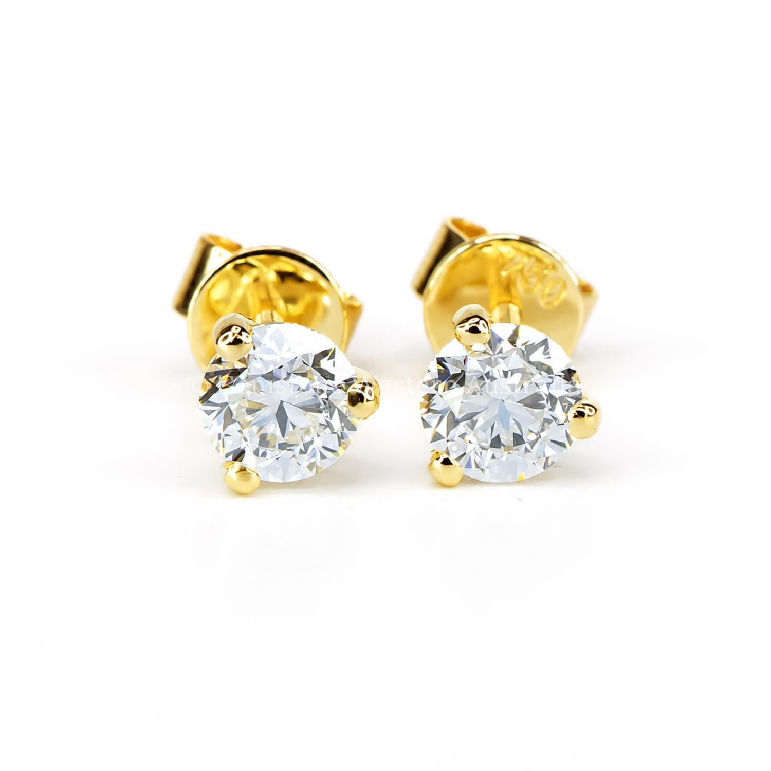A pair of diamond stud earrings set in yellow gold on a white background 